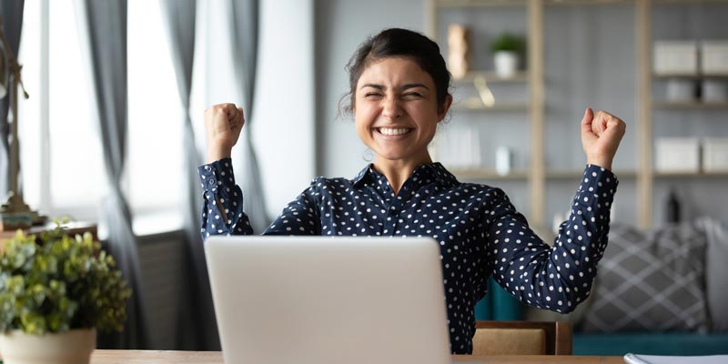 Woman celebrating in front of laptop